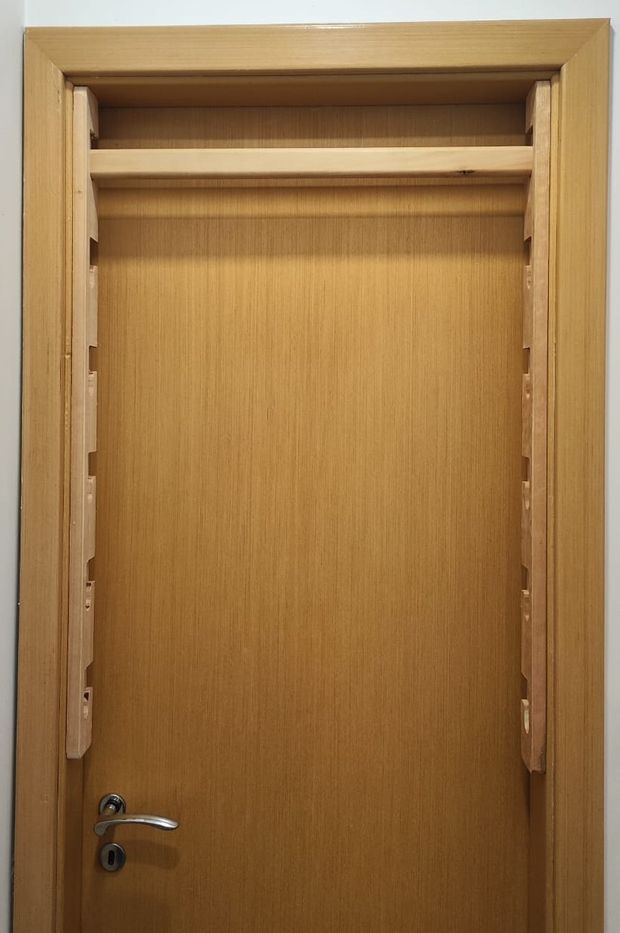 Os dois trilhos parafusados nos batentes da porta, com a barra encaixada na posição mais alta
